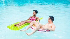 Two people floating on a pool with clear water.