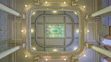 Un techo imponente y ricamente decorado, con un ventanal central de vitrales, rodeado por columnas simétricas y molduras ornamentales.