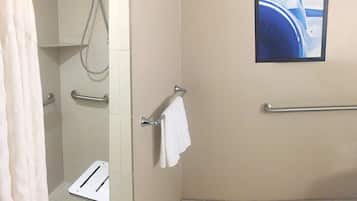 A bathroom with a shower, grab bars, a towel rack, and a picture on the wall.