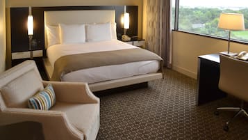 Habitación de hotel con una cama grande, un escritorio, una silla y vistas al exterior.