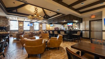 Un restaurante con suelos de madera, sillas de cuero, una zona de bar y una pantalla de televisión.