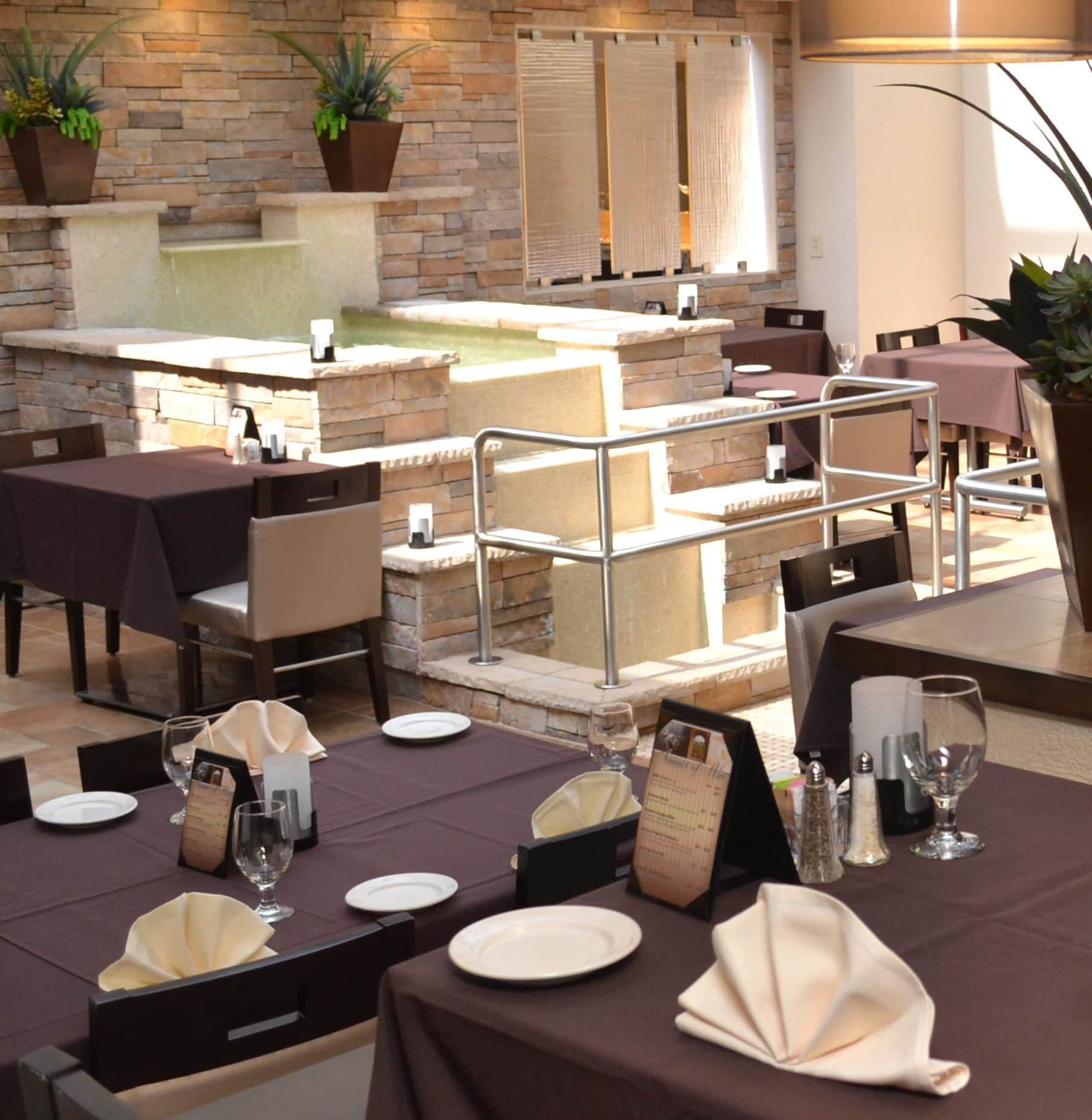 An outdoor dining area with stone walls, multiple tables, and chairs.