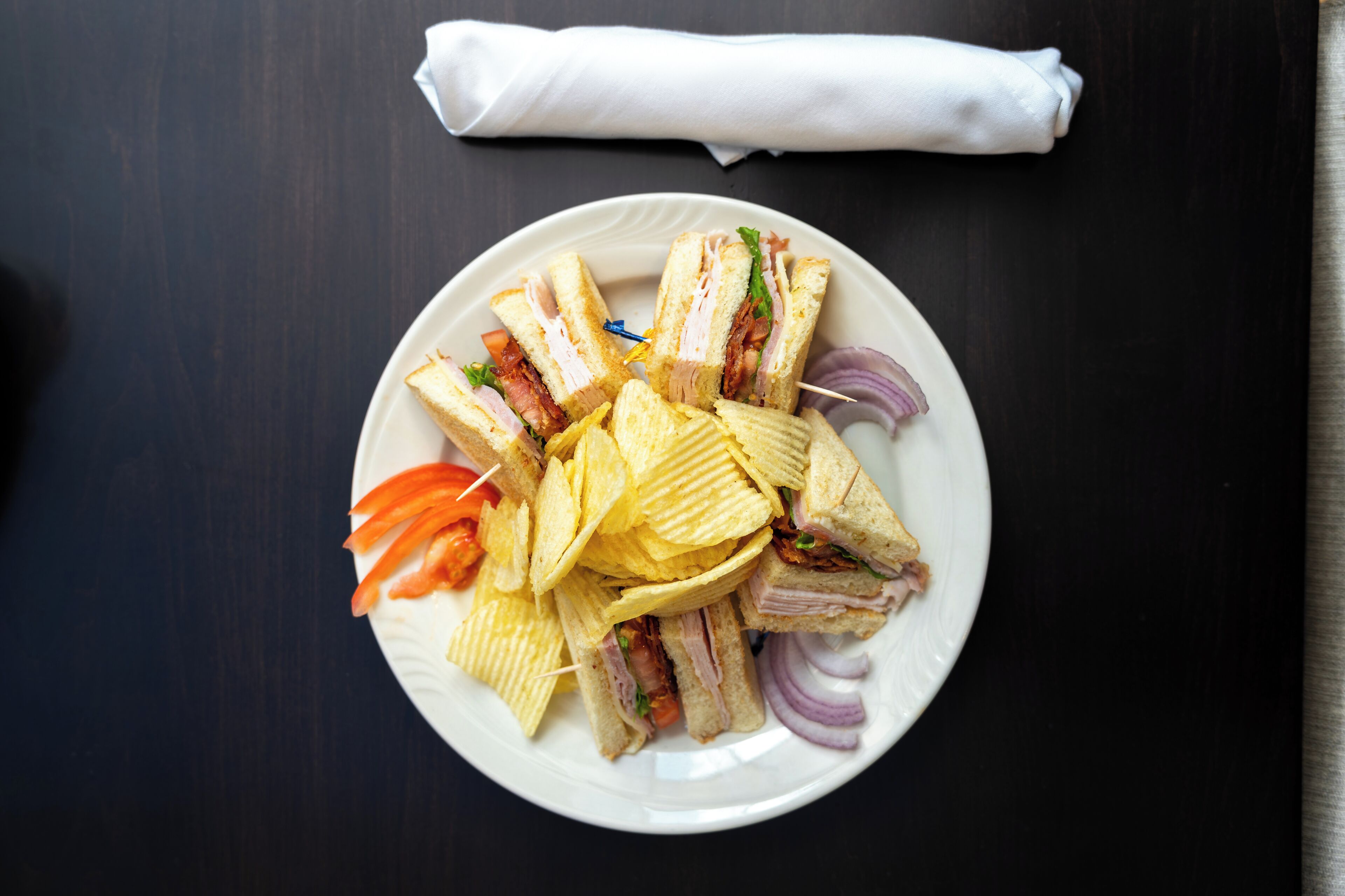 A plate of sandwiches and chips on a table.