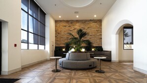A lobby with a large window, a stone wall, a circular seating area, and a patterned floor. - Doubletree by Hilton Houston Hobby Airport (Houston)