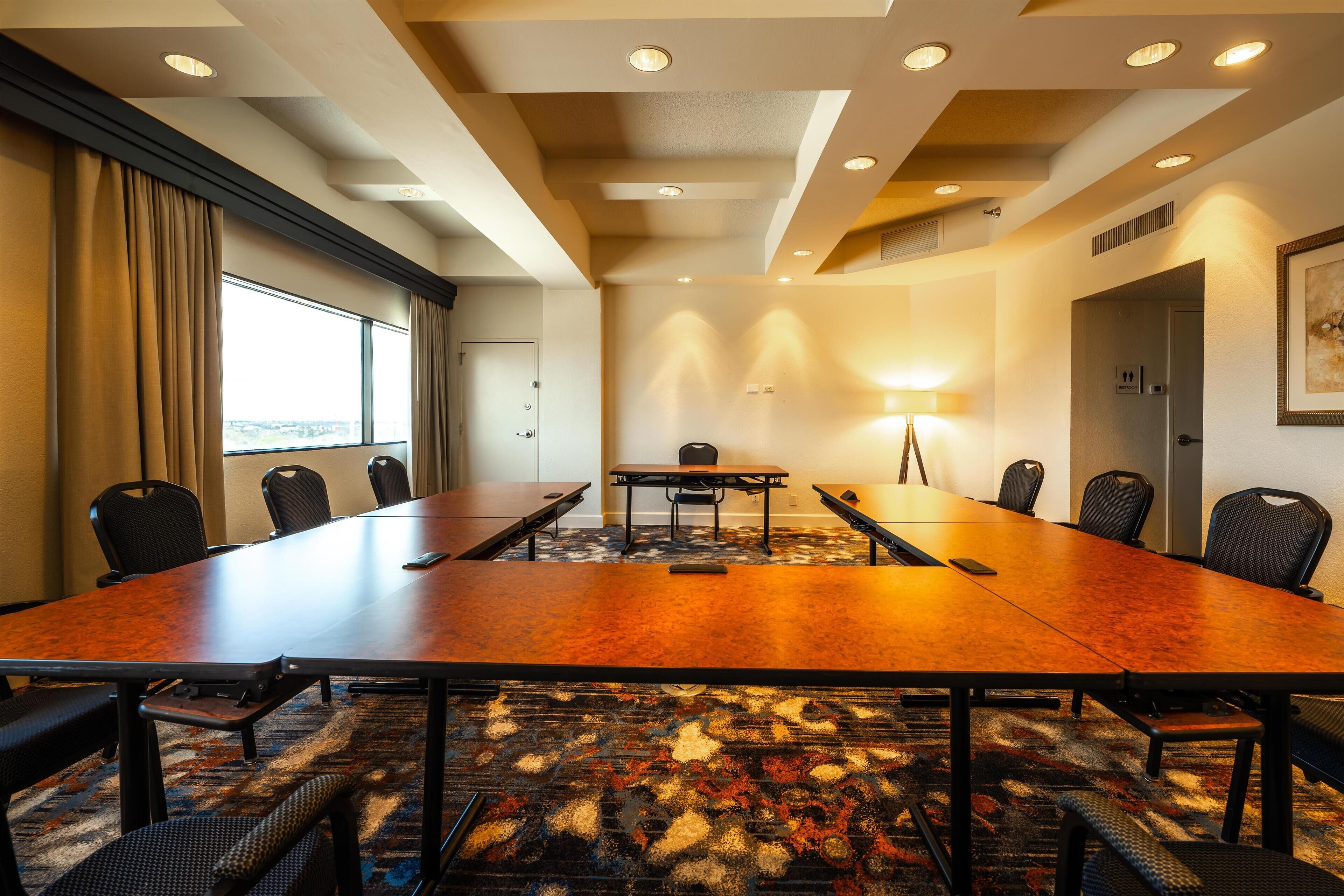 Une salle de conférence avec une longue table, des chaises, une lampe et une porte.