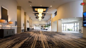 A spacious hotel lobby with a large chandelier, a reception desk, and a view of the outdoors through large windows. - Doubletree by Hilton Houston Hobby Airport (Houston)