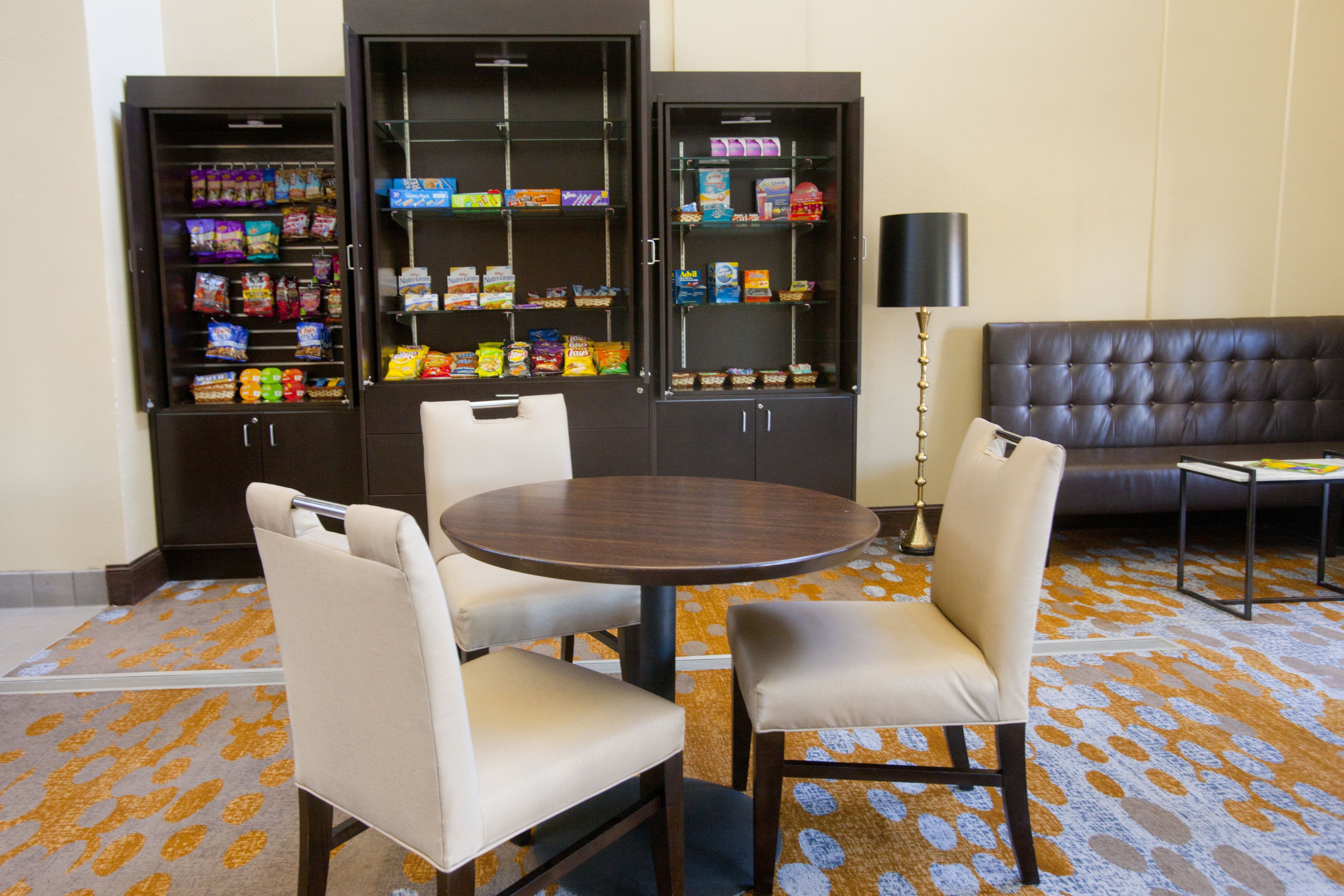 Een eetgedeelte met een ronde tafel en twee stoelen, een bank en twee automaten voor snacks.