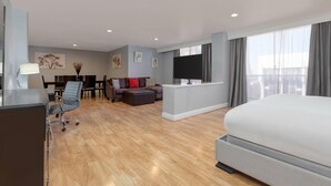 A modern hotel room with a large bed, a desk with a chair, a sofa, and a dining area. - Wyndham Midland Downtown (Midland)