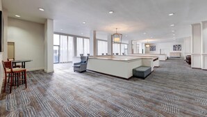 A spacious hotel lobby with a central island, seating areas, and large windows providing natural light. - Wyndham Midland Downtown (Midland)