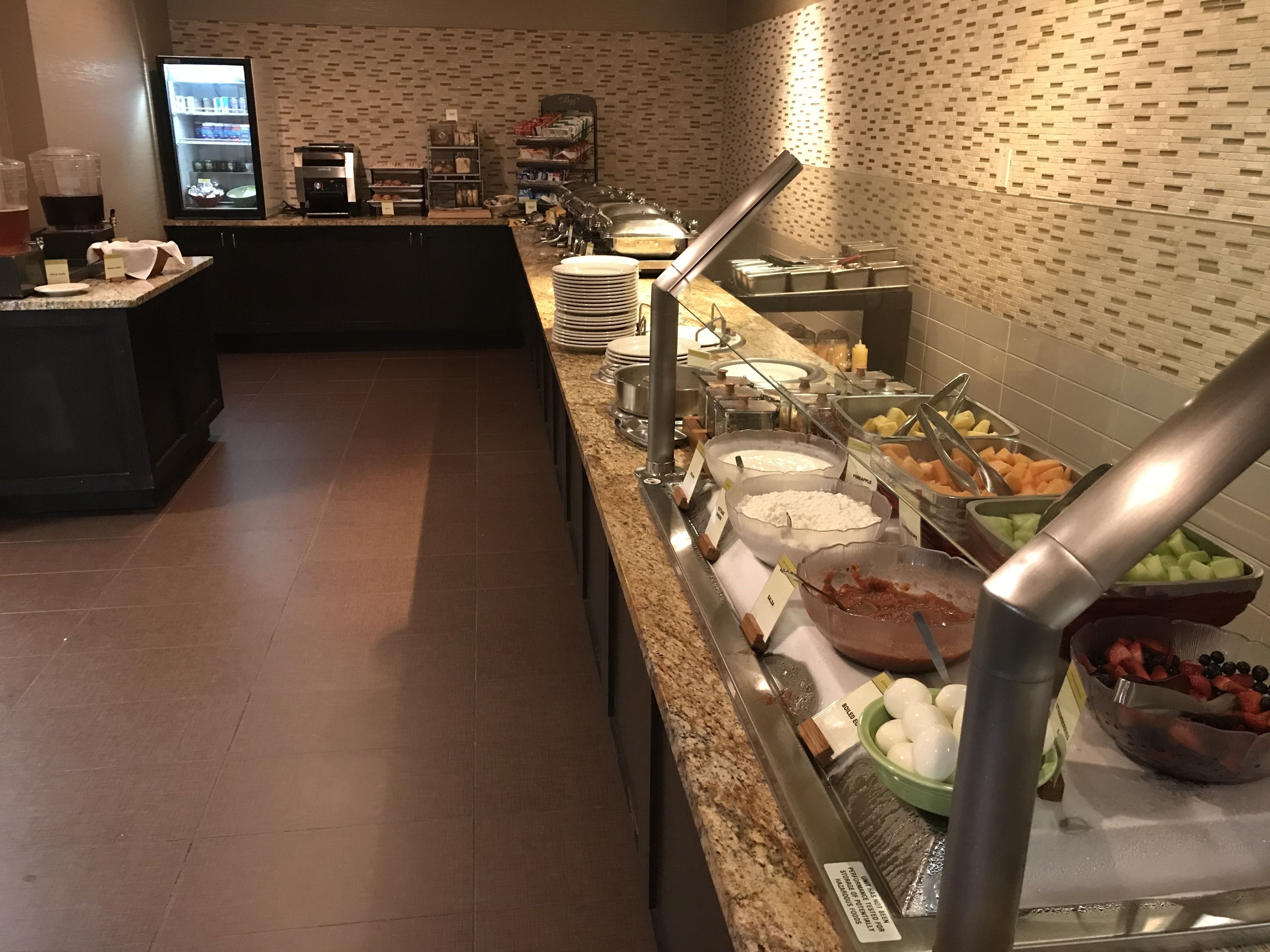 A buffet area with various food stations, including fruits, cheeses, and other items.