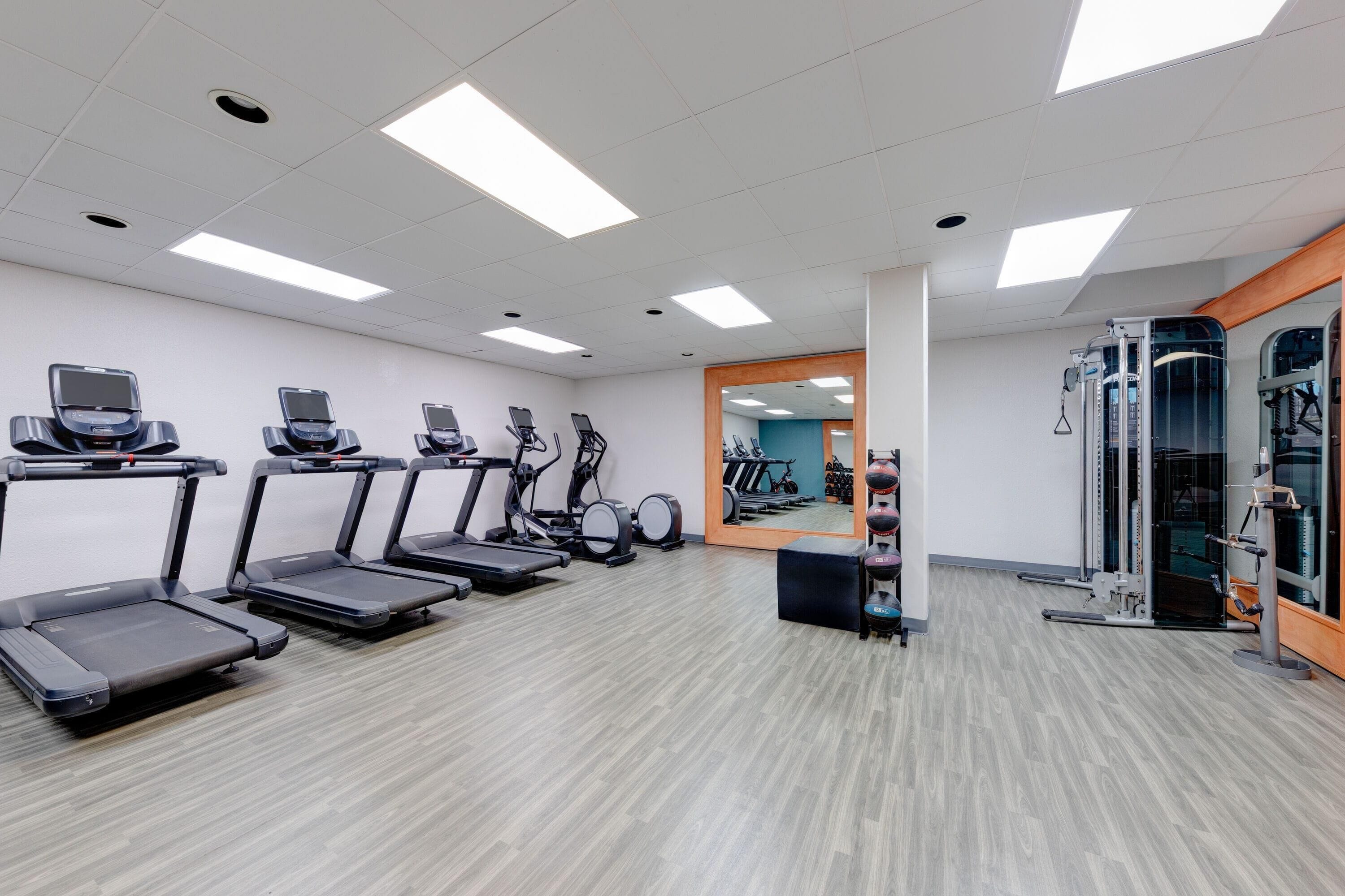 Une salle de sport équipée de tapis de course, de vélos elliptiques et de matériel de musculation.