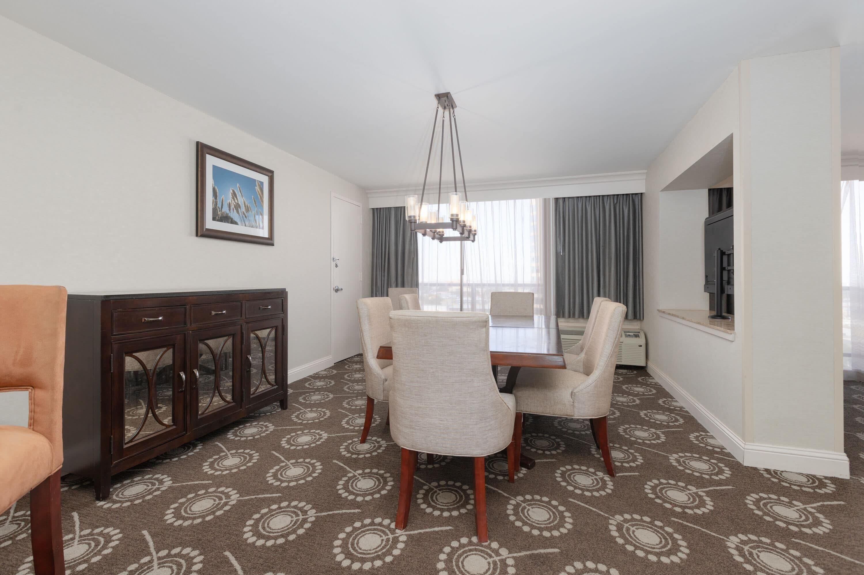 A dining area with a table and chairs, a cabinet, and a chandelier.