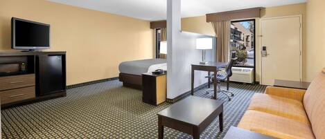 A hotel room with a bed, a desk, a TV, a sofa, and a small table.