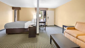 A hotel room with a bed, a desk, a chair, a sofa, and a small table.