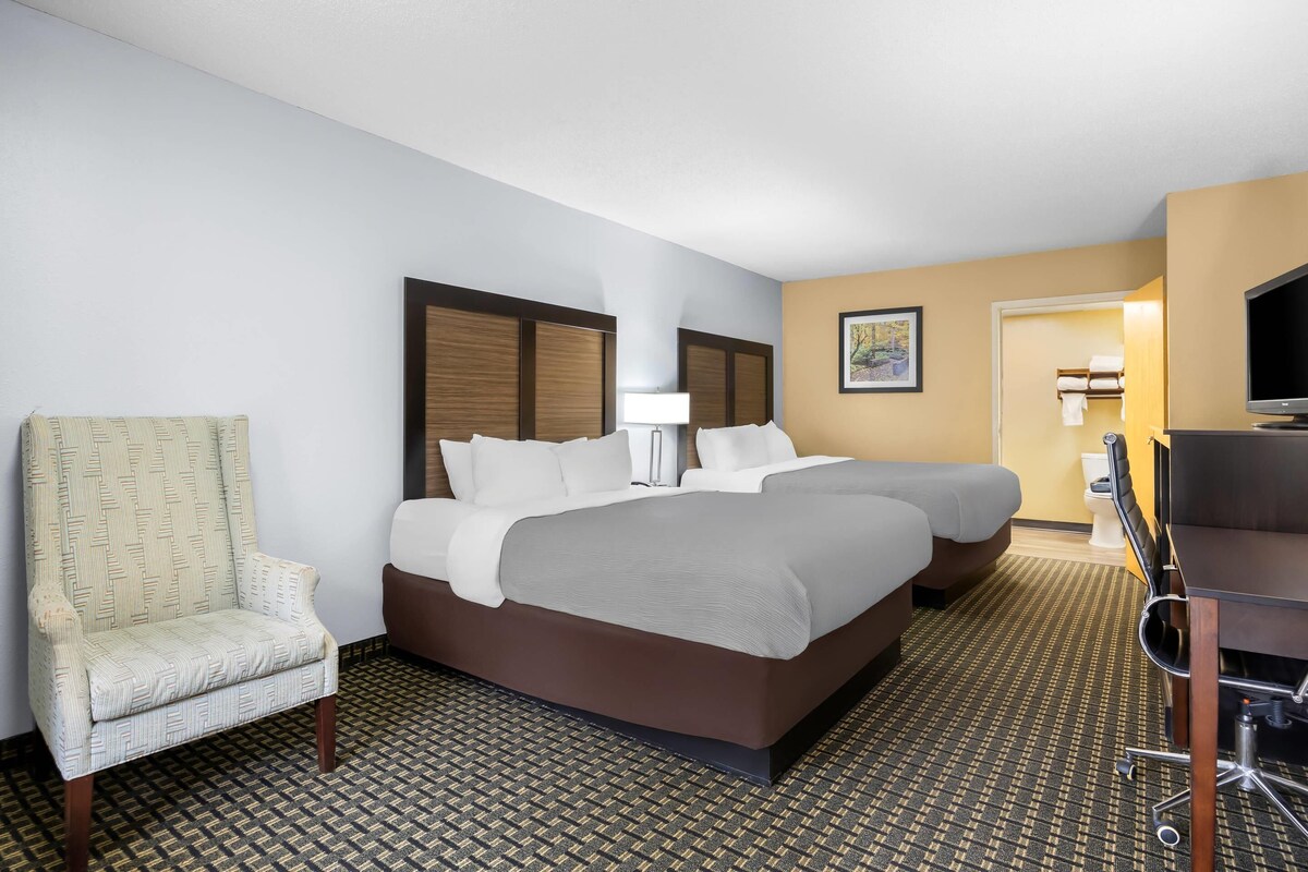 A hotel room with a large bed, a chair, a desk, and a television.