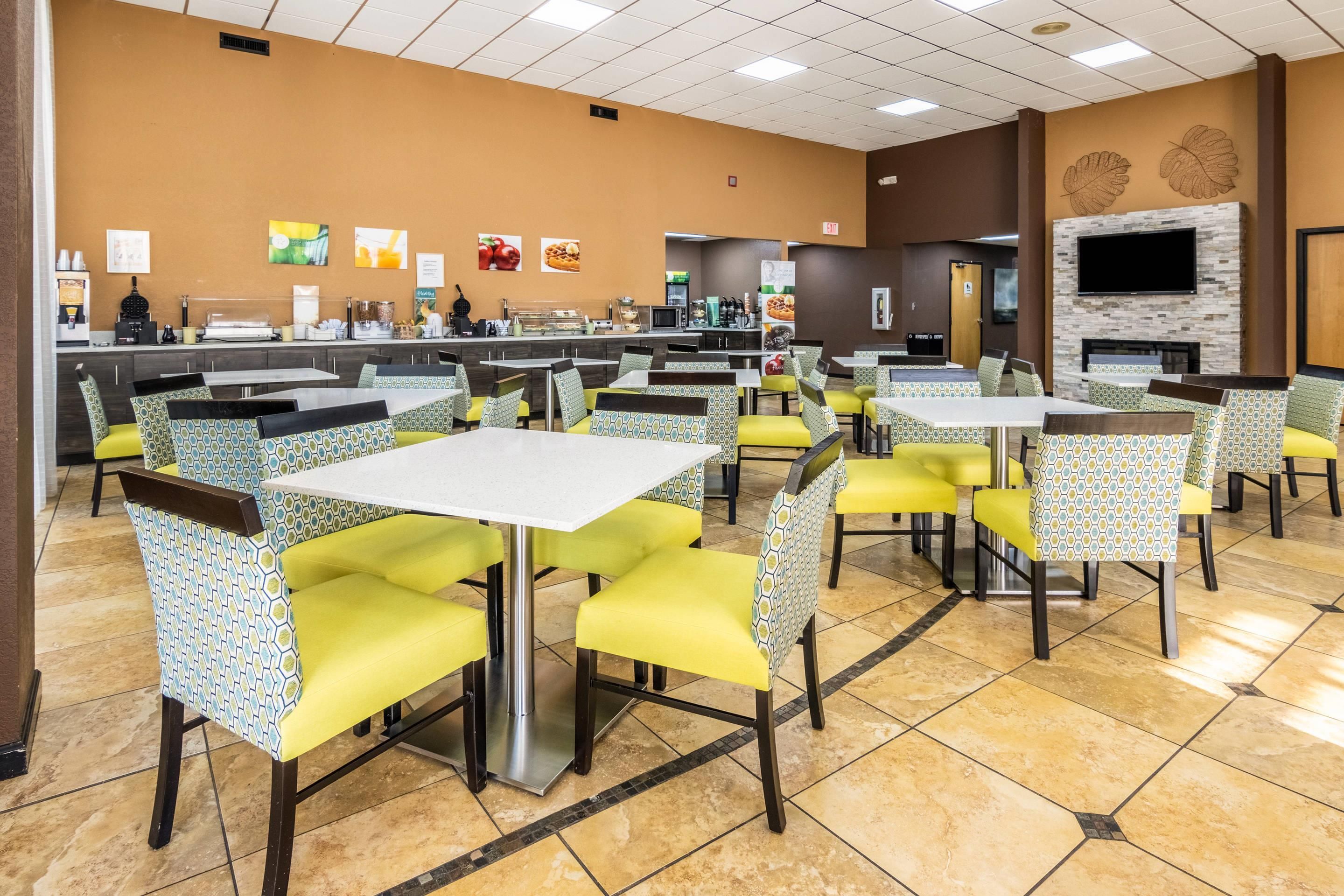 A restaurant with multiple tables and chairs, a counter with food items, and a television mounted on the wall.