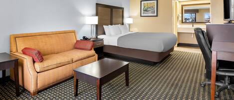 A hotel room with a bed, a sofa, a desk, and a chair.