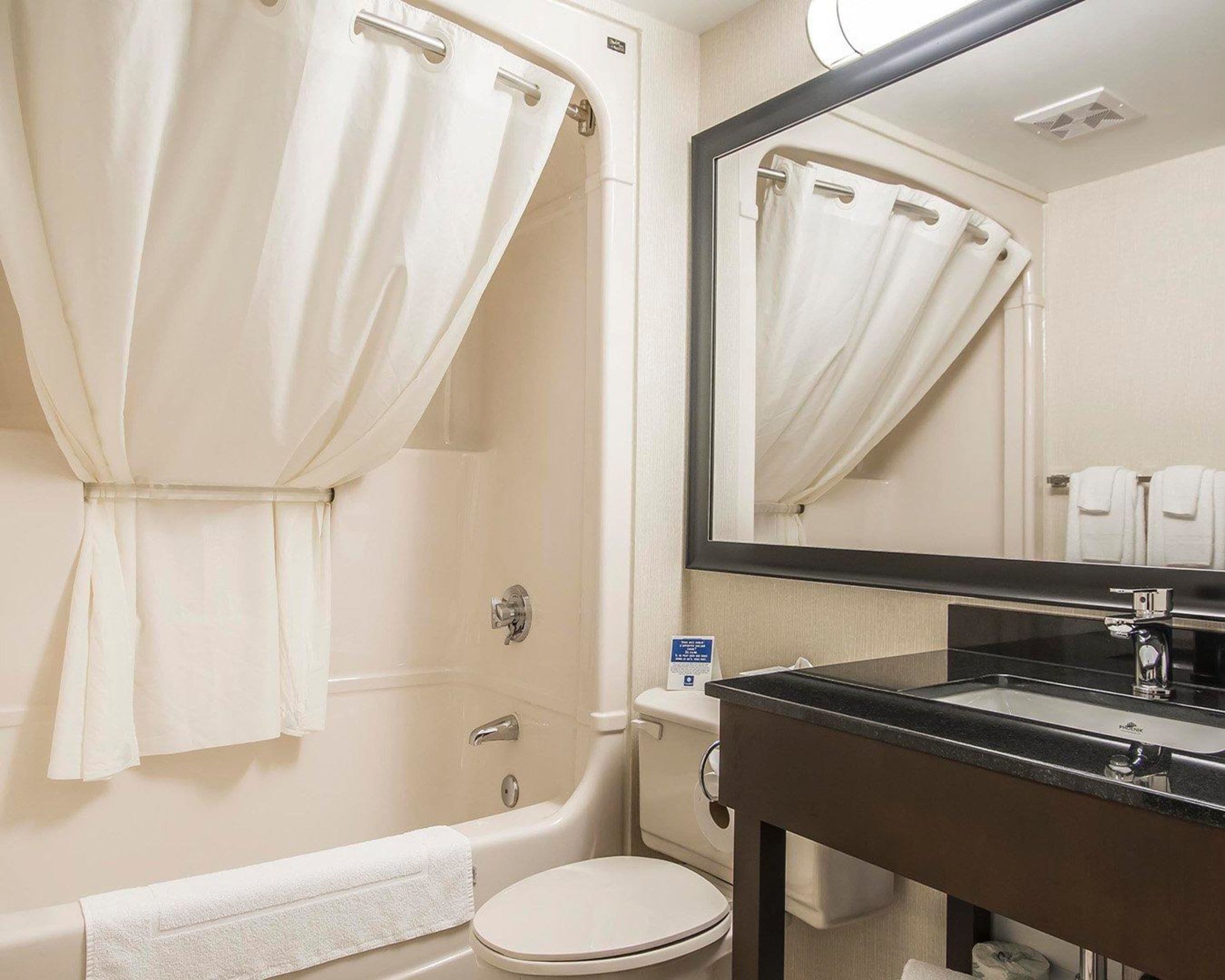 A bathroom with a bathtub, toilet, sink, and a mirror.