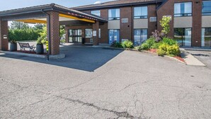 A building with a covered entrance, outdoor seating, and a landscaped area with plants.