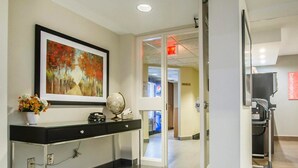 A reception area with a desk, a globe, a framed painting, and a vase of flowers. - Comfort Inn Rimouski (Rimouski)