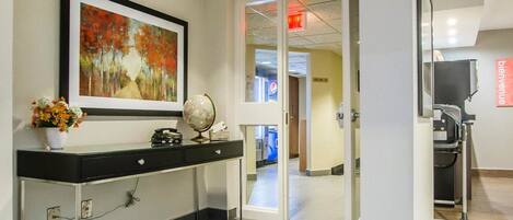 A reception area with a desk, a globe, a framed painting, and a vase of flowers.