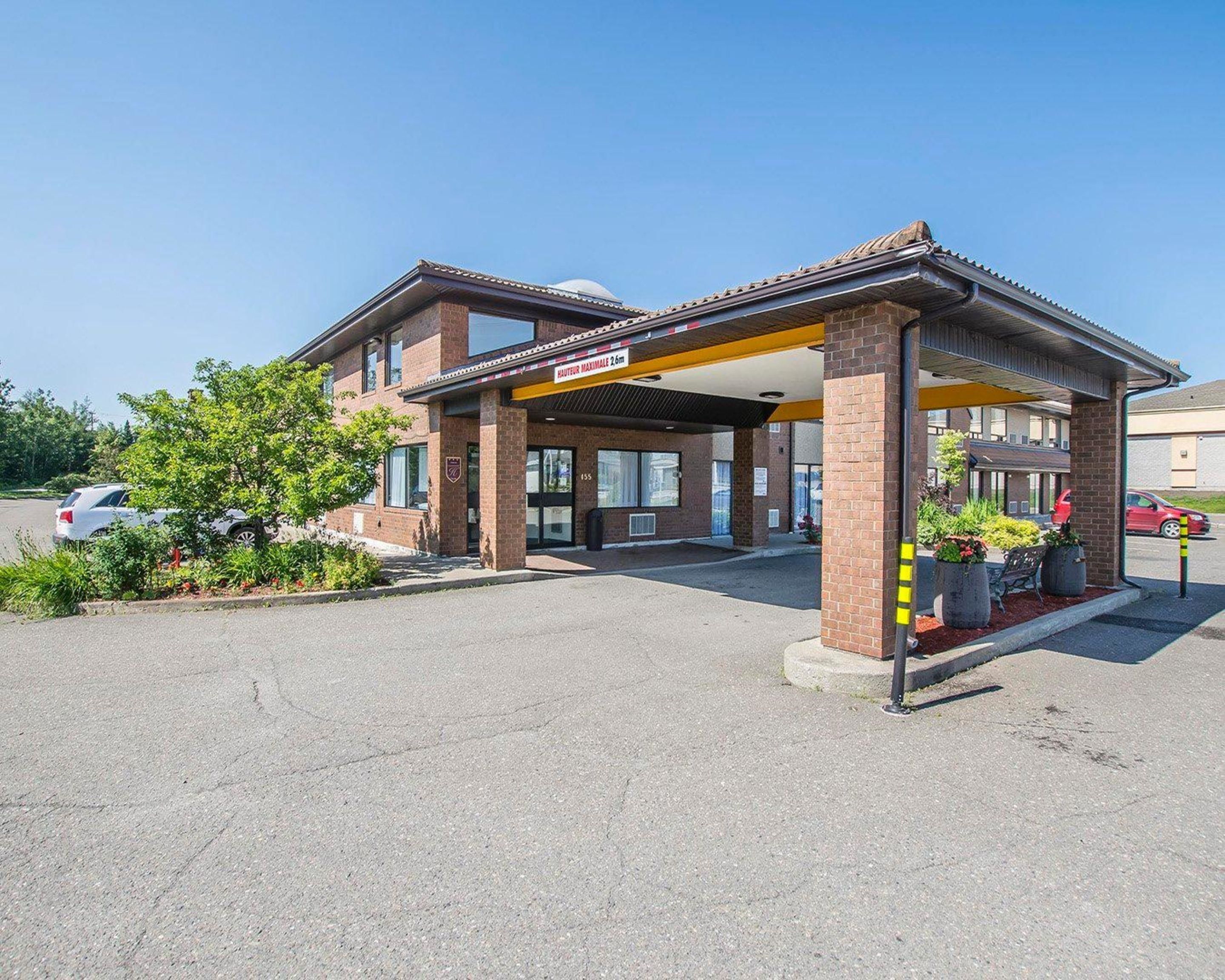 A brick building with a covered entrance and a sign indicating it is a hotel.