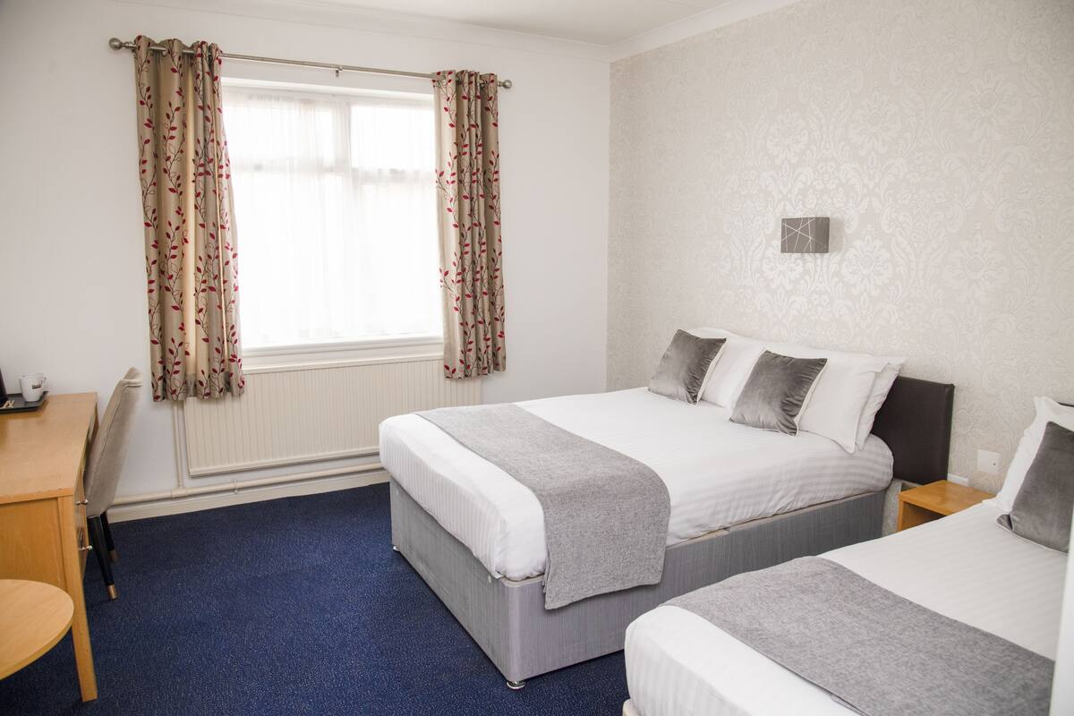 A hotel room with two beds, a desk, and a chair.