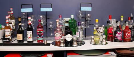 Een bar met verschillende drankflessen en glazen, waaronder merken als Monin, Smirnoff, Hendrick's en LUXA.