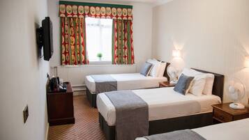 A hotel room with two beds, a desk, a chair, a TV, and a window with curtains.