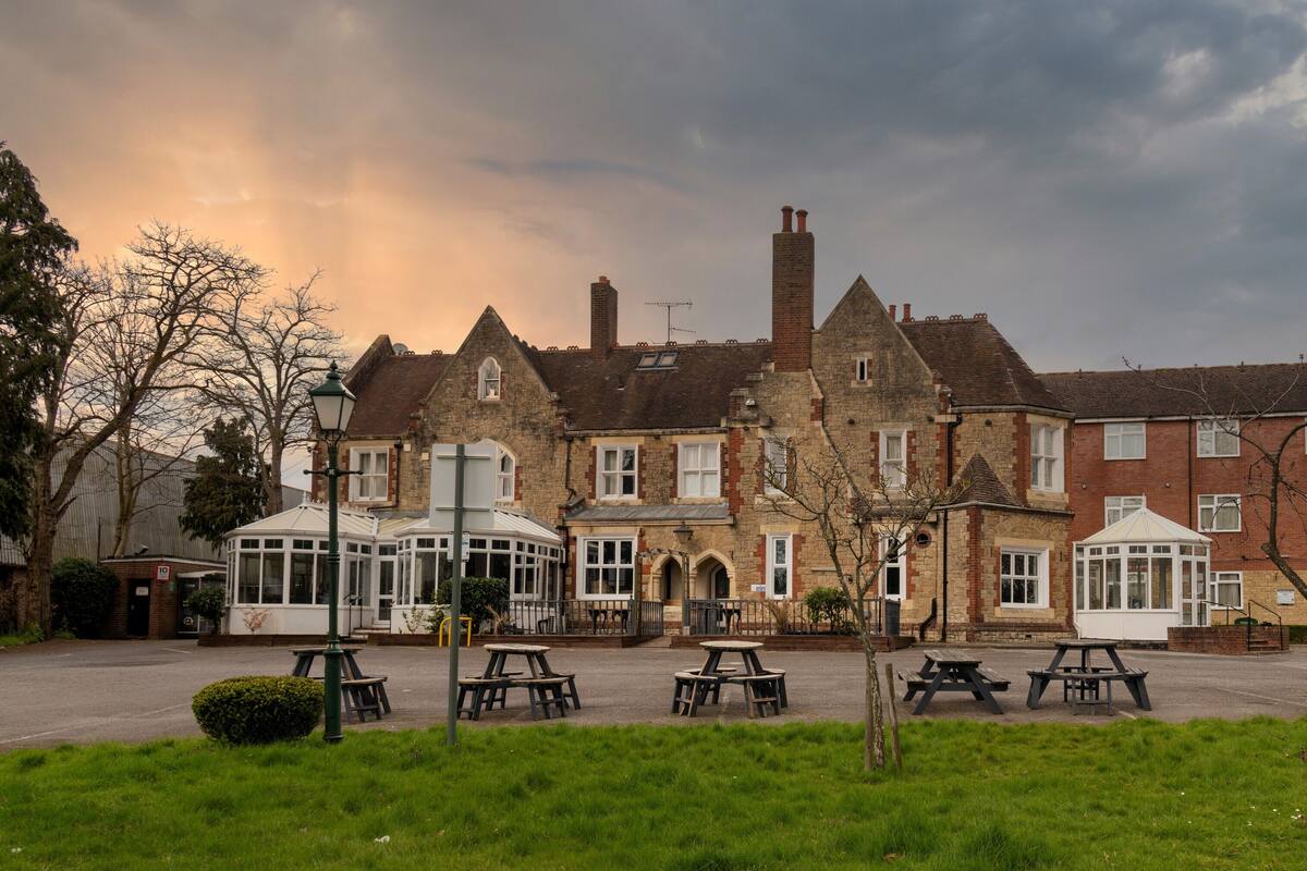 A traditional building with multiple windows and a courtyard with picnic tables.