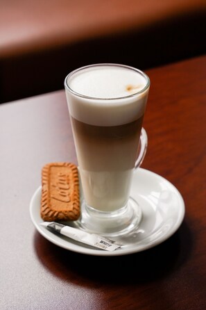 A glass of coffee with a biscuit on a white saucer. - Hamlet Hotels Maidstone (Aylesford)