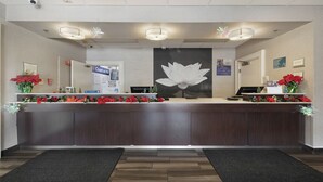A reception area with a wooden reception desk, a large white lotus flower decoration, and red poinsettia plants.