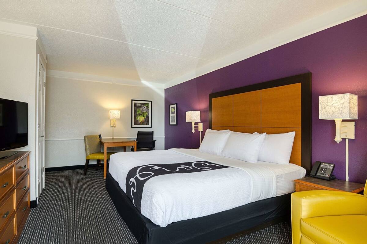 Een hotelkamer met een bed, een bureau, een stoel, een televisie en een telefoon.