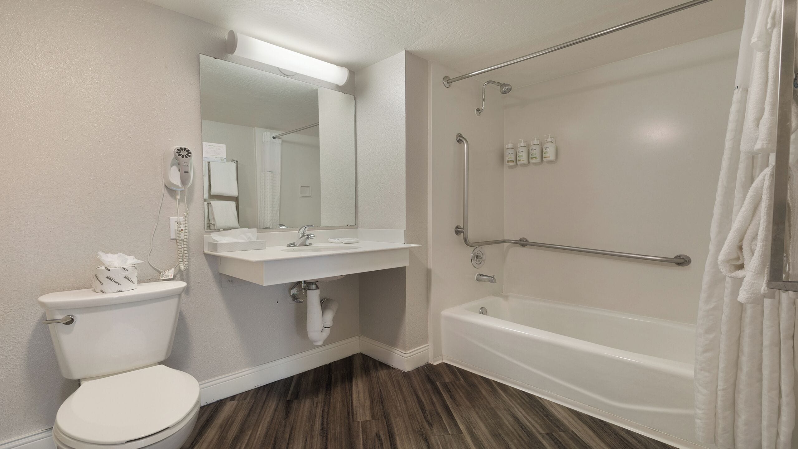 A bathroom with a toilet, sink, mirror, and bathtub.