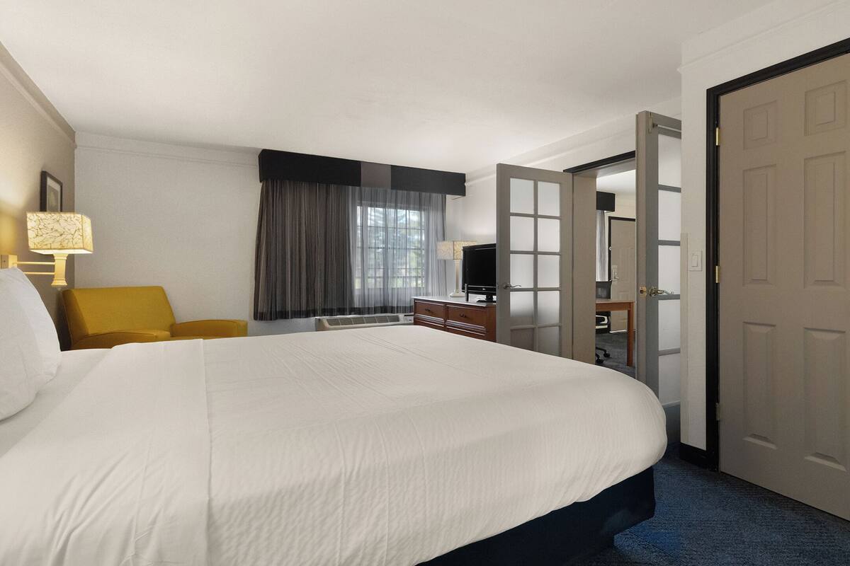 Een hotelkamer met een groot bed, een bureau met een computer, een stoel en een kledingkast.