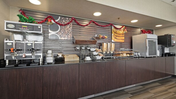 A commercial kitchen with espresso machines, a coffee station, and holiday decorations.