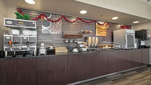A commercial kitchen with espresso machines, a coffee station, and holiday decorations.
