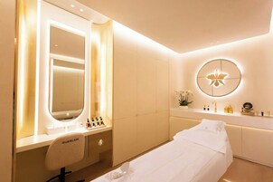 Een moderne slaapkamer met een kaptafel, een grote spiegel, een bed en een ronde spiegel aan de muur.
