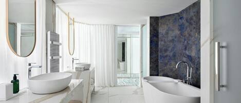 A modern bathroom with a large freestanding bathtub, a vanity with a white sink, and a mirror.