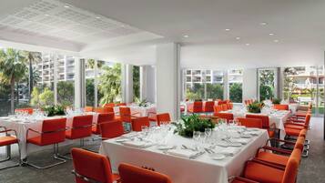 A dining area with tables set for a meal, large windows, and a view of the outdoors.