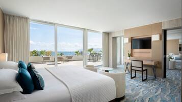 Een moderne hotelkamer met een groot bed, een bureau en uitzicht op de oceaan.