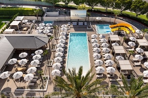 An aerial view of a resort with a central swimming pool, sun loungers, umbrellas, and a slide. - Hyatt Regency Irvine (Irvine)