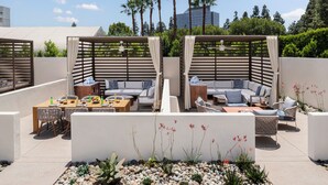 Una terraza en la azotea con mobiliario exterior, zona de comedor y un jardín rocoso decorativo.