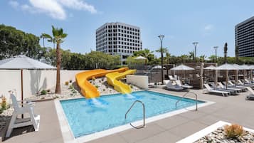 Una piscina al aire libre, camas de piscina con cargo, sombrillas