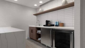 Una cocina moderna con azulejos blancos tipo metro, estantes de madera, un refrigerador de acero inoxidable y una encimera blanca.