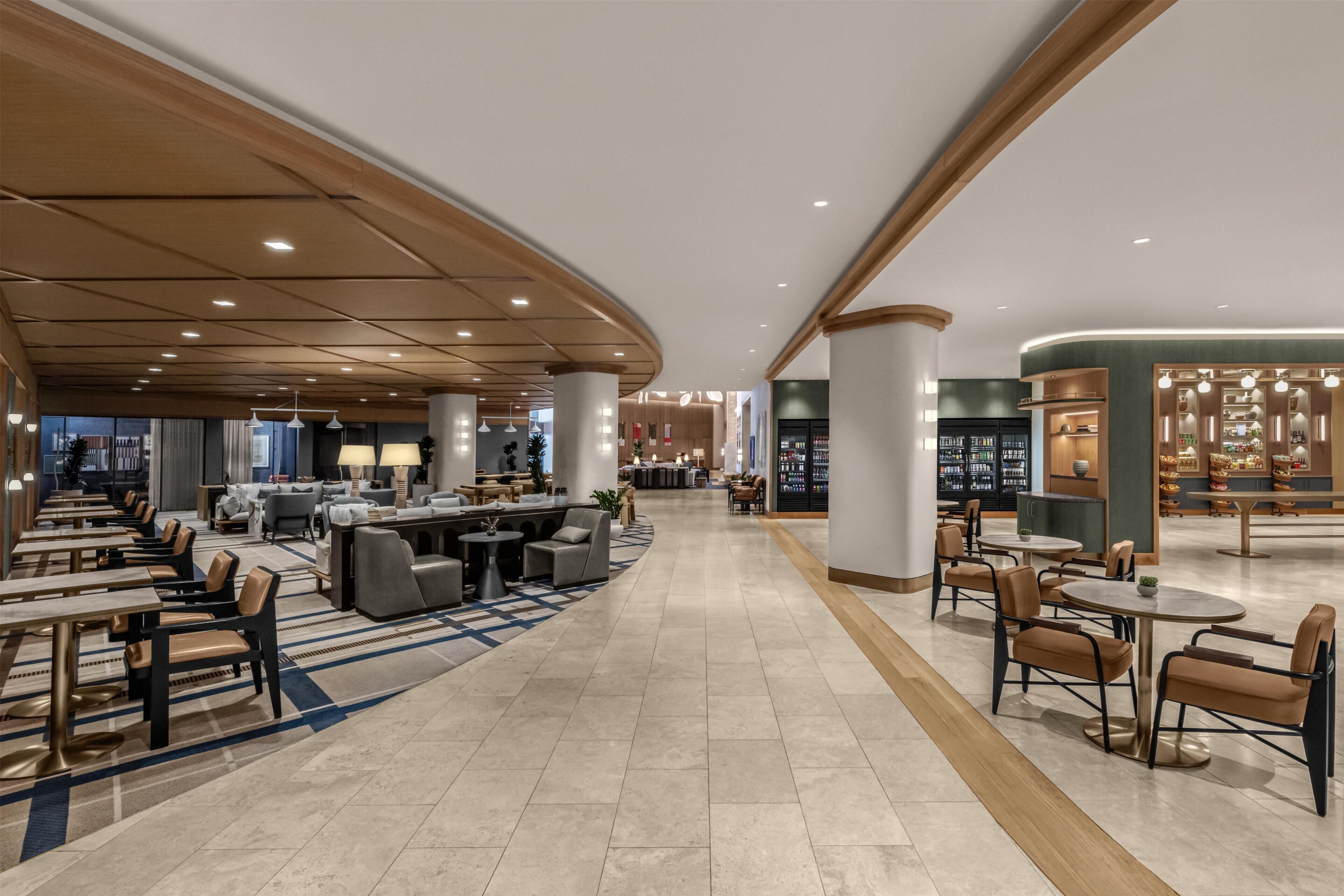 A spacious hotel lobby with multiple seating areas, a central bar, and a well-lit ceiling.