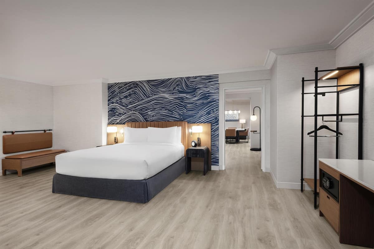 Ein modernes Hotelzimmer mit einem großen Bett, Nachttischen, einem Schreibtisch und einem Kleiderschrank.