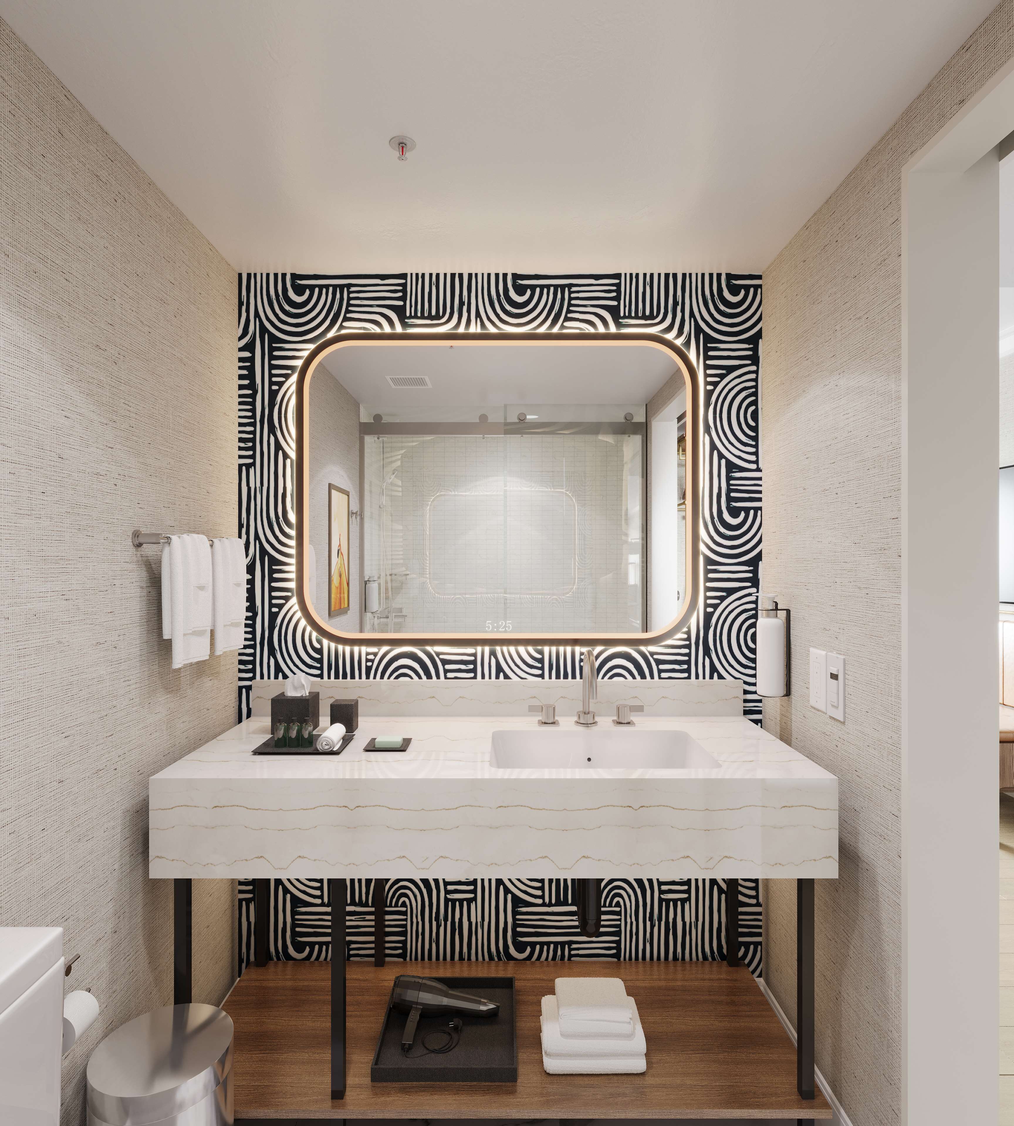 Un baño moderno con un espejo grande, lavamanos de mármol blanco y azulejos con diseño.