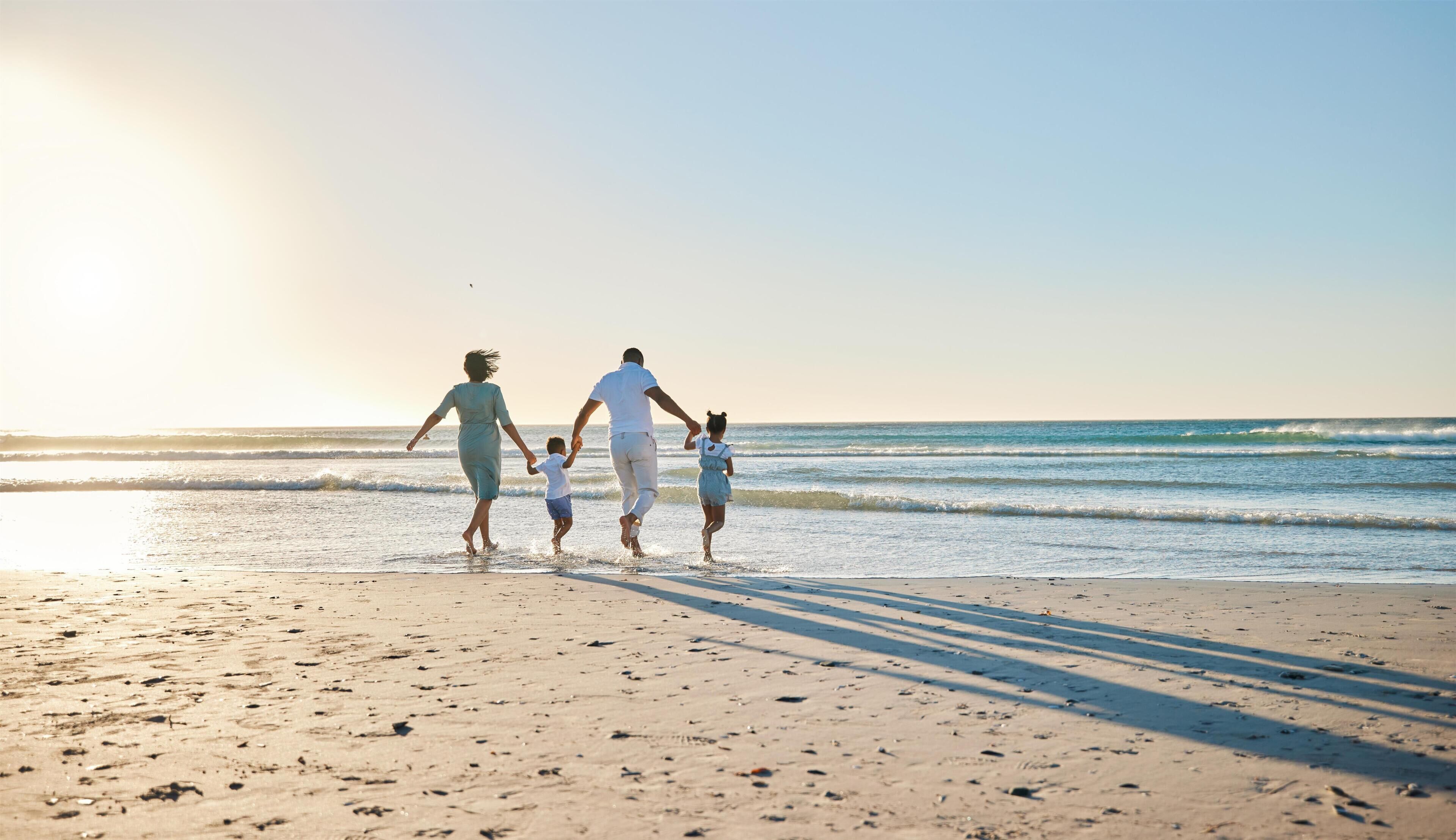 Escena de playa con una familia caminando por la orilla.