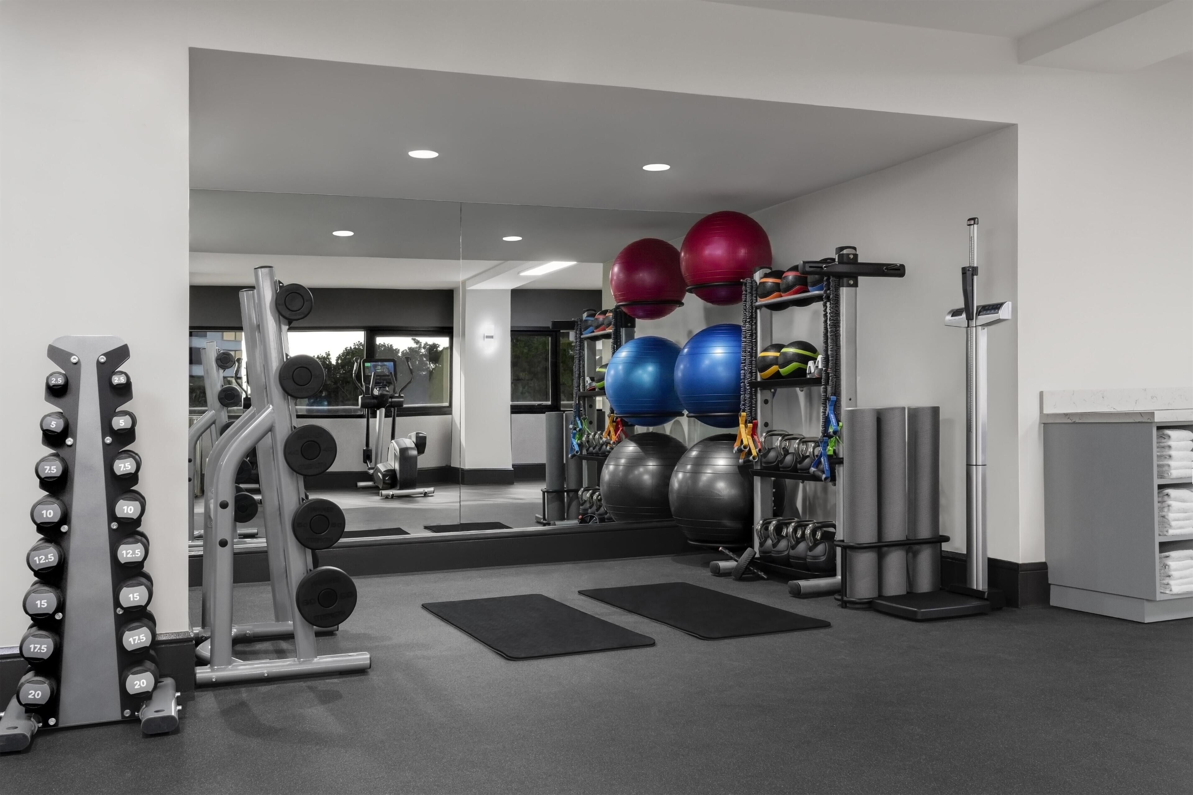 A gym with weightlifting equipment, exercise balls, and a mirrored wall.